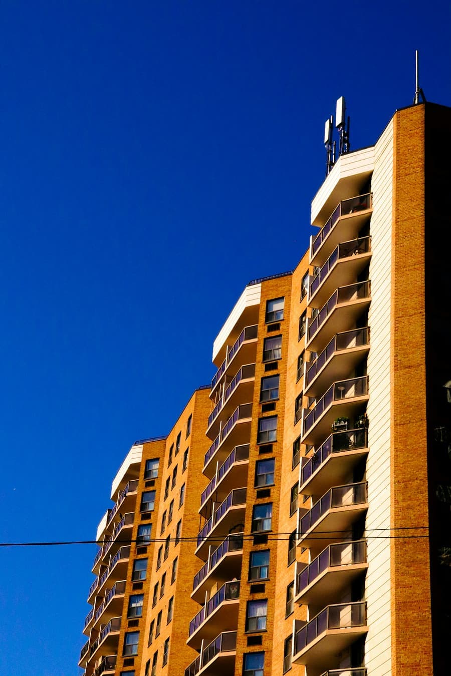 A brick apartment tower with balconies against a blue sky